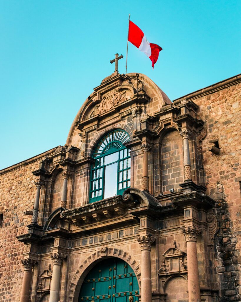 Perú ante la OCDE: ¿Examen de progreso o Crónica de un Estancamiento? Stone facade of a historic building in Cusco, Peru with the national flag waving atop.