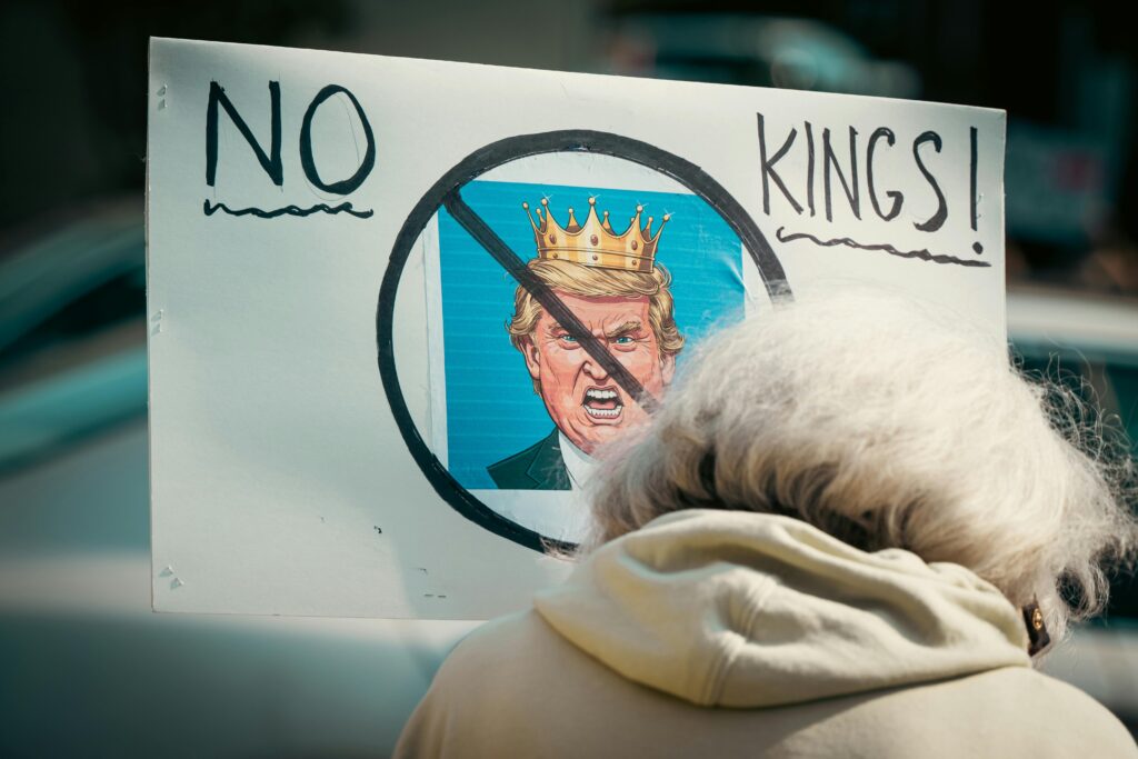 Gobernanza Global: El retorno de la ultraderecha en el escenario mundial A protest sign reading 'No Kings' depicts resistance against monarchy with a satirical image.
