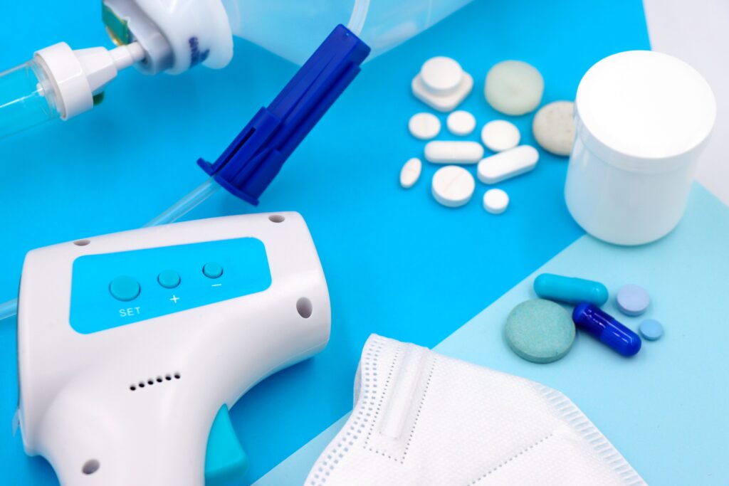 El costo de la salud: ¿Se pueden tener precios éticos para la medicina? A collection of medical supplies including pills, a mask, and a thermometer on a blue surface.