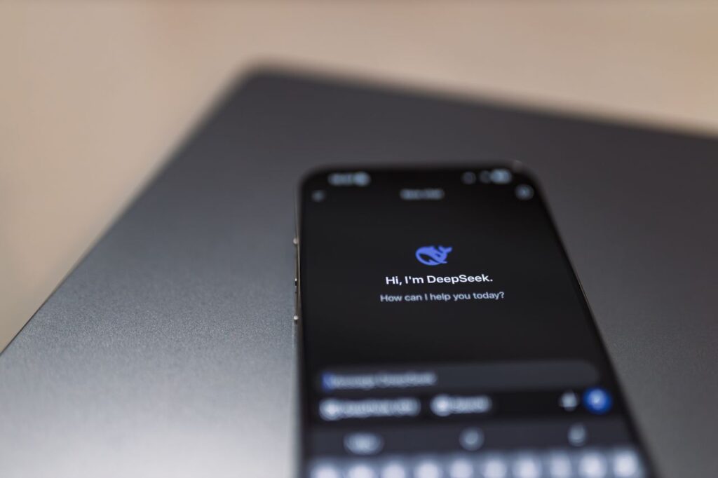 La IA como objeto regulado: El impacto del marco europeo en la Inteligencia Artificial Close-up of a smartphone with AI assistant interface on screen over a laptop.